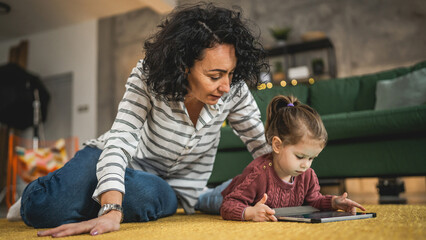 Mother and daughter use digital tablet to watch online video at home