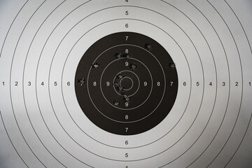 A paper target for shooting with holes from 9mm pistol bullets in the center, close-up photo.
