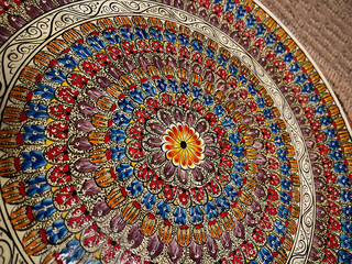detail of a ceramic plate decorated with a colorful circular pattern, with floral and animal motifs,  horizontal, Decorative porcelain plate painted with acrylic paints, handwork