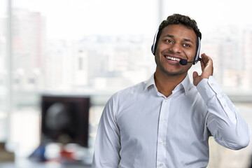 Smiling male call center agent talking to customer. Call center operator at work. Blur office...