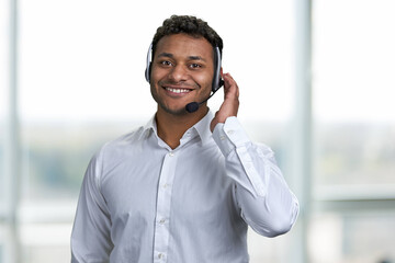 Friendly male call center operator in headset talking with customer. Young business operator man...