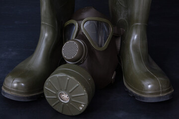 An old gas mask amidst military rubber boots, a haunting reminder of past conflicts and the...
