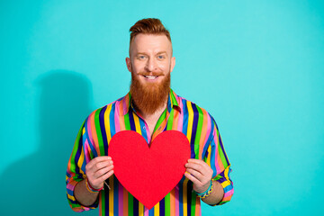 Portrait of optimistic lover handsome red hair hipster boyfriend holding paper heart postcard...