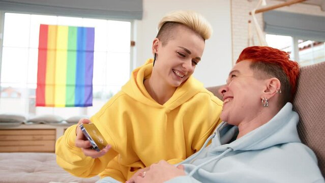 In a serene home setting, a lesbian couple shares a profound moment, revealing an ultrasound image of their future child, with a backdrop of the Pride flag symbolizing their journey and hope.