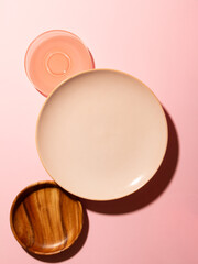 Top view of various ceramic dishes on pink background