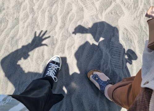 Black sneakers and sandals walking on white Sand top view, White canvas shoes and sandals walking on white Sand