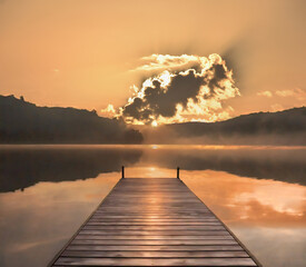 Wooden pier on a lake with a huge cloud front of the sun at sunrise in the misty morning