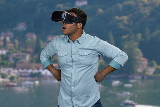 Surprised young man wearing virtual reality glasses. Blur sea and mountains in the background. - Powered by Adobe