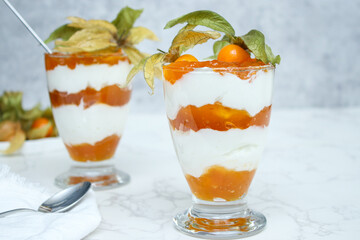Two glasses of layered dessert with protein yoghurt and physalis fruit - obrazy, fototapety, plakaty
