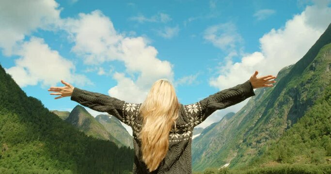 Mountains, open arms or woman hiking in nature adventure to explore on outdoor holiday vacation. Traveller, gratitude or back of hiker trekking with backpack for travel, freedom or journey in Norway