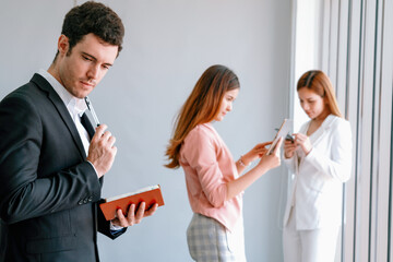 Fototapeta na wymiar Happy young handsome businessman reading book and working in office with colleagues and friend at workplace. Corporate business people group. uds