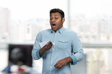 Young indian man about to sneeze. Blur interior background. Flu or allergy symptoms.