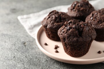Delicious chocolate muffins on grey textured table, closeup and space for text
