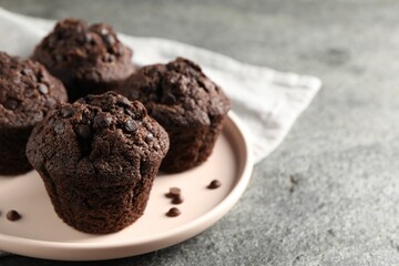 Delicious chocolate muffins on grey textured table, closeup and space for text
