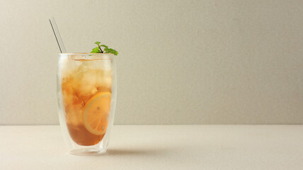 ICed Lemon Tea on Cream Background with Glass Straw