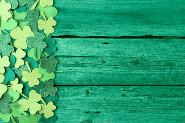 St. Patrick's day. Decorative clover leaves on green wooden background, top view. Space for text