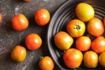 Tomatoes or rangam are plants from the Solanaceae family, plants native to Central and South America, from Mexico to Peru. tomatoes in a black plate. Solanum lycopersicum