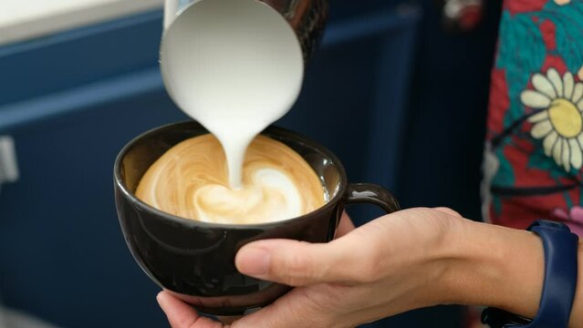 closeup hand doing hot latte art coffee
