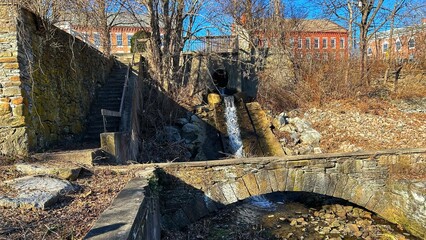 Old Rock Stair Walkway with Railing and Water Spillway Run Off Running Under Stone Arch in Old Mill...