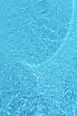 Water surface. Bluewater waves on the surface ripples blurred. Defocus blurred transparent blue colored clear calm water surface texture with splash and bubbles. Water waves with shining pattern.