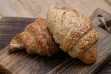 croissants on a wooden cutting board. croissant, which originated in France, is so named because of its shape resembling a crescent moon. made from wheat, eggs, salt, margarine. whole wheat. 