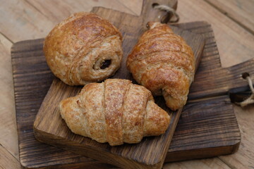 whole wheat croissants on wooden cutting board. croissant, which originated in France, is so named because of its shape resembling a crescent moon. made from wheat, eggs, salt, margarine.