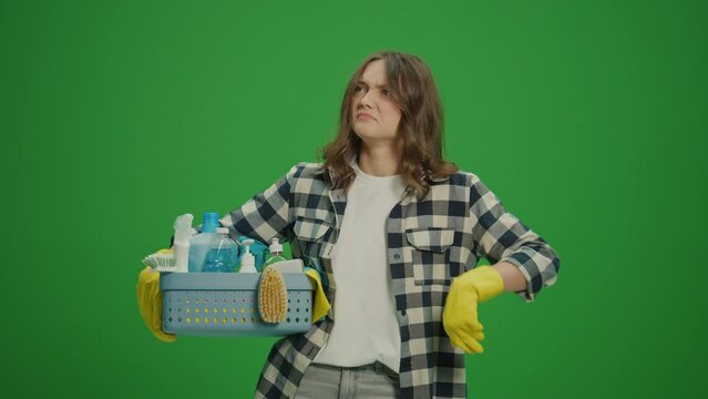 Green Screen.A Portrait of a Displeased Young Woman in Yellow Gloves Holding a Box With Cleaning Products, Smelling a Bad Smell. Pet-friendly Cleaning Solutions.
