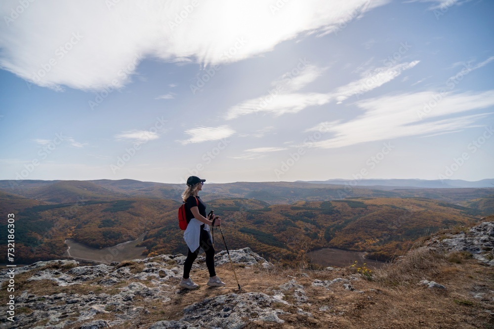 Wall mural woman on mountain peak looking in beautiful mountain valley in autumn. Landscape with sporty young woman, blu sky in fall. Hiking. Nature