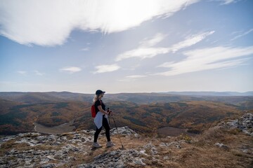 Obraz premium woman on mountain peak looking in beautiful mountain valley in autumn. Landscape with sporty young woman, blu sky in fall. Hiking. Nature
