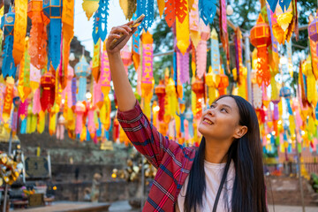 Asian woman tourist using mobile phone taking selfie or vlogging during travel old Buddhist temple in Chiang Mai. Attractive girl enjoy outdoor lifestyle travel Thailand on summer holiday vacation.