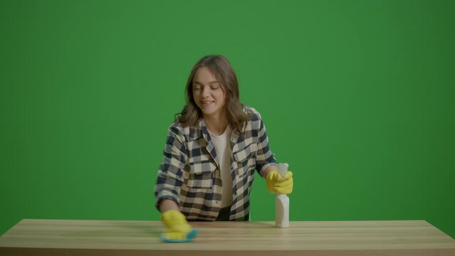 Green Screen.A Smiling Young Woman Housewife Cleaning the Table with a Spray Bottle and a Rab,Enjoying Cleaning. Efficient Work-from-home Setups.