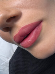 permanent makeup on the lips of a young woman of a delicate peach shade close-up, a girl after a cosmetic procedure with smooth and clean healthy skin. - obrazy, fototapety, plakaty