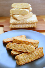 Plate of pan fried Tempeh with Stack of the Uncooked in the Backdrop