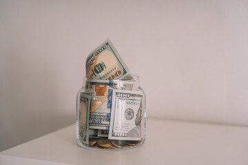 Glass jar with paper bills and coins against a white background.