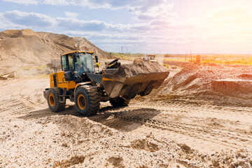 Open pit mine quarry, yellow excavator transporting sand with sunlight. Concept heavy machinery of...