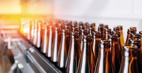 Brown glass beer drink alcohol bottles, brewery conveyor, modern industrial food production line banner with sunlight