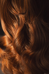 Woman head showcasing styled auburn hairstyle with soft waves. Detailed view of shiny hair highlighting its natural curls and texture background - obrazy, fototapety, plakaty