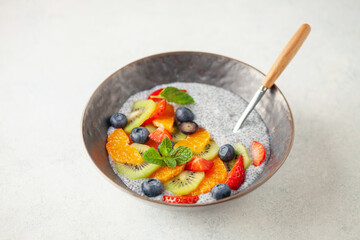 Chia puddind with fruit berry salad in bowl on grey background. Healthy breakfast