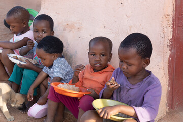 group of village african children eating in the yard, famine and malnutrition NGO solving world problems © poco_bw