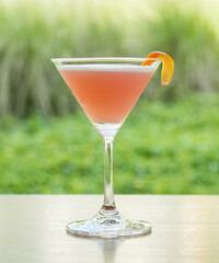 Martini glass with pink cocktail on wooden table