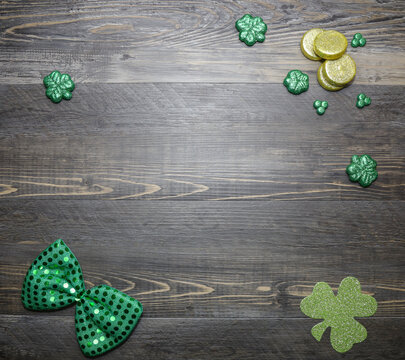 St Patrick's day wooden background with shamrocks, green bow tie and gold coins. Copy space, space for text.