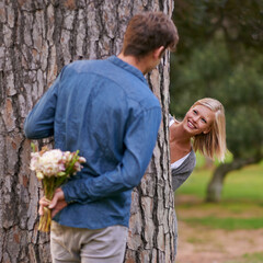 Couple, park and love for valentines day with flower in romance, boyfriend for girlfriend. Romantic, outdoor and date to play with hide and seek for bonding, happiness and relax for wellness
