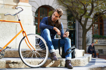 Obraz premium Man in city, bicycle and cellphone with travel, carbon footprint and communication with tech and cycling. Eco friendly transportation, using phone for location and connectivity for journey with bike