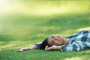Space, thinking or woman on grass in park to relax for rest in garden, nature or field alone for peace. Mockup, ideas or happy female person on break with smile on outdoor vacation or holiday on lawn