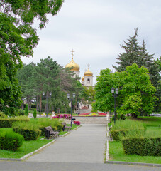 an alley in the park with an Orthodox church in the background