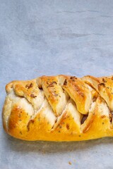 Pizza braid. Delicious braided pizza bread stuffed with cheese, bacon, ham and tomato or barbecue sauce on white baking paper.