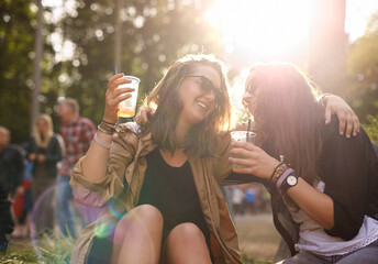 Beer, laughing and woman friends in nature together with audience or crowd at event, festival or...