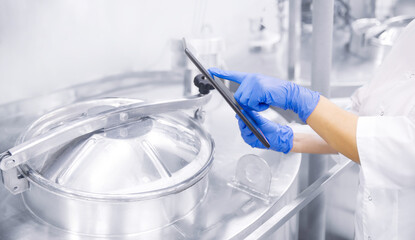 Quality supervisor on modern production food factory. Worker inspector using tablet for checking tank, banner of industry