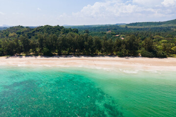 Beautiful coastline with blue waters, powdery white sand and many pine trees.