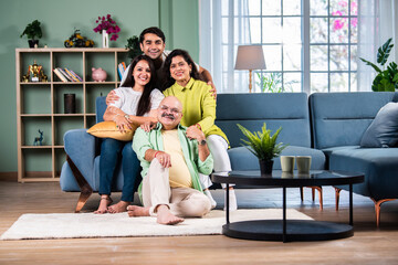Portrait of happy Indian family of four sitting in modern living room - Powered by Adobe